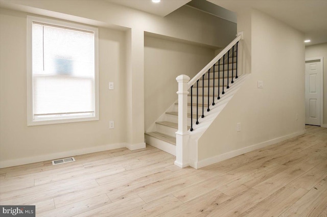 stairs with baseboards, visible vents, plenty of natural light, and wood finished floors
