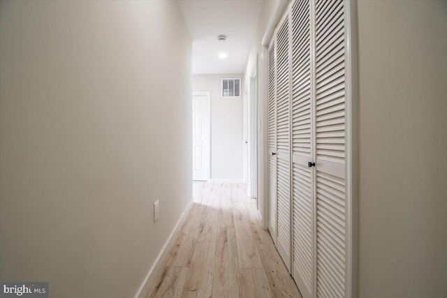 hall with visible vents, light wood-style flooring, and baseboards