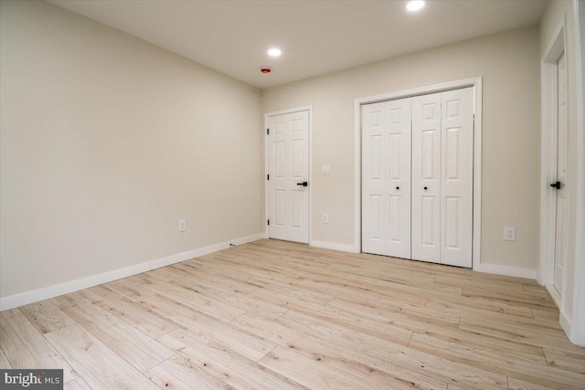 unfurnished bedroom featuring recessed lighting, baseboards, a closet, and light wood-style floors