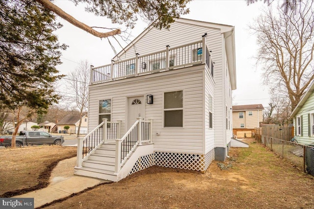 view of front of property with fence and a balcony