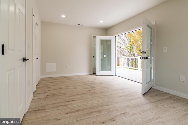 interior space with light wood-type flooring, baseboards, visible vents, and access to exterior