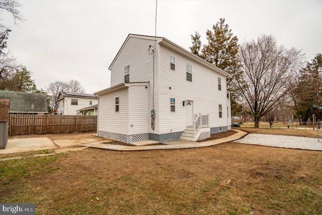 rear view of house featuring fence and a yard