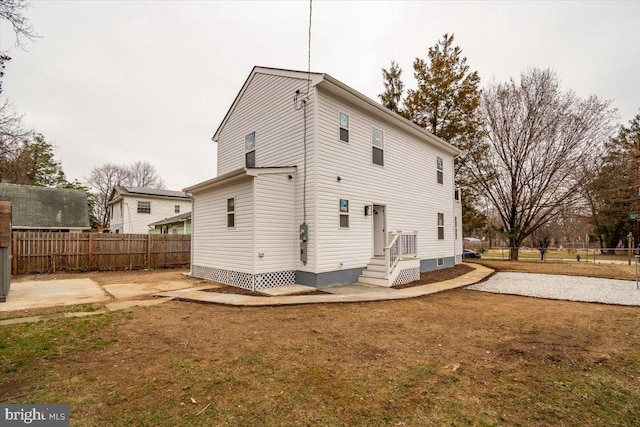 rear view of property featuring a lawn and fence