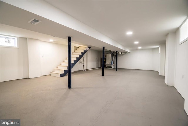 basement with stairs, recessed lighting, visible vents, and heating unit