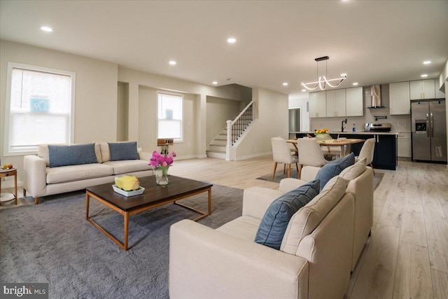 living room with stairs, recessed lighting, a chandelier, and light wood-type flooring