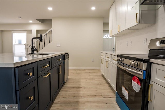 kitchen featuring light wood-style floors, light countertops, white cabinetry, a sink, and appliances with stainless steel finishes