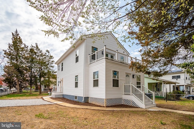 view of front of home featuring fence and a balcony