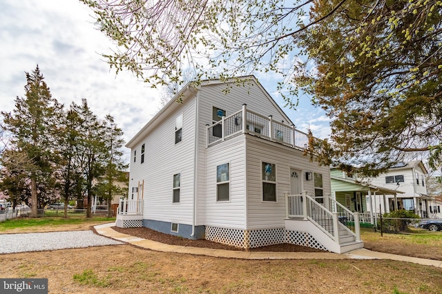 view of side of property featuring fence and a balcony