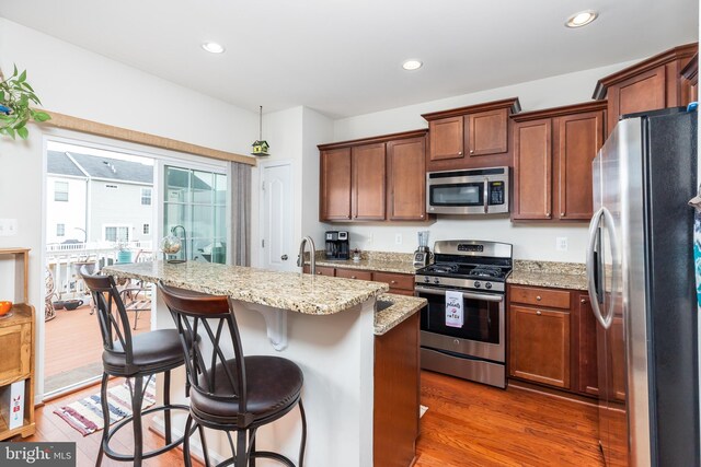 20422 Asheville Dr, Millsboro, DE 19966 - kitchen with a kitchen breakfast bar, wood finished floors, recessed lighting, appliances with stainless steel finishes, and light stone countertops