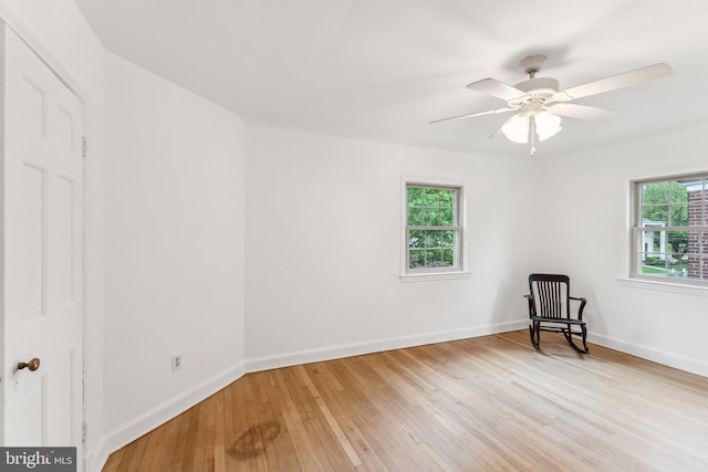unfurnished room featuring baseboards, light wood-type flooring, and a wealth of natural light