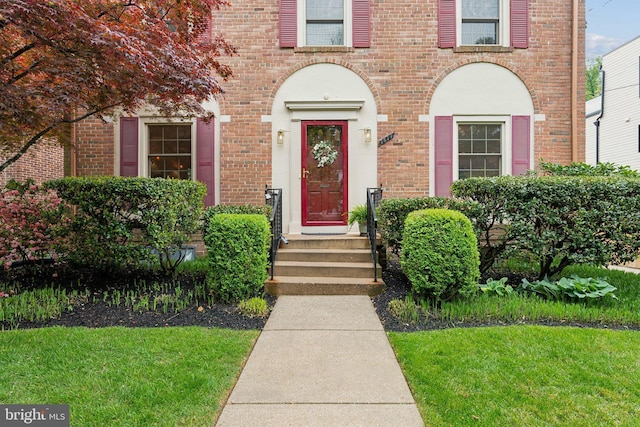 property entrance with a lawn and brick siding