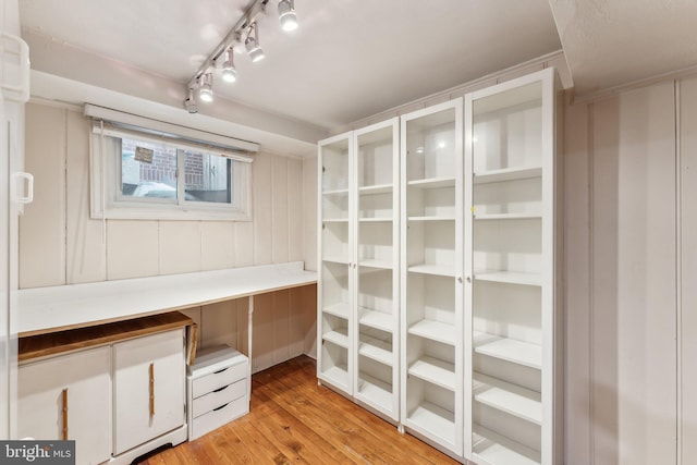 unfurnished office featuring light wood-style flooring and a decorative wall