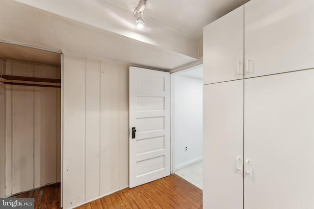 unfurnished bedroom with wood-type flooring and track lighting