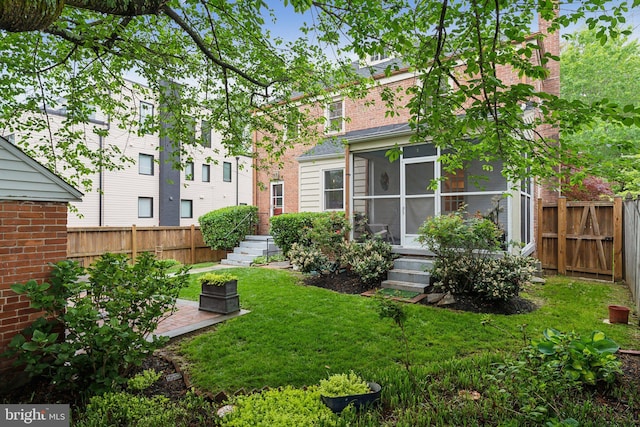 rear view of house with a yard, fence, and a sunroom