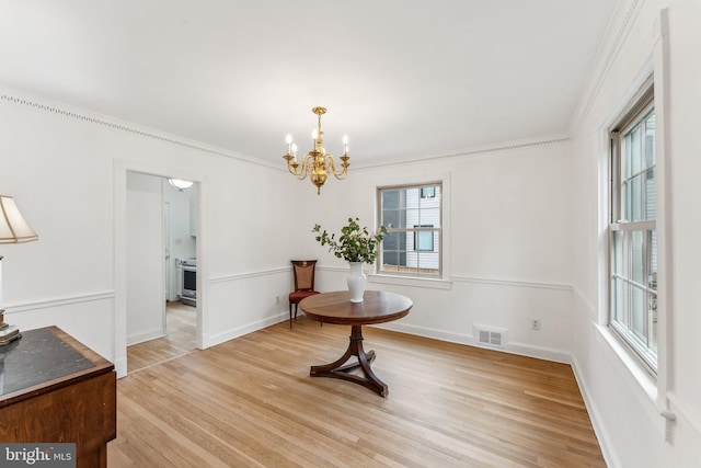 dining area with crown molding, a notable chandelier, visible vents, and light wood-style flooring