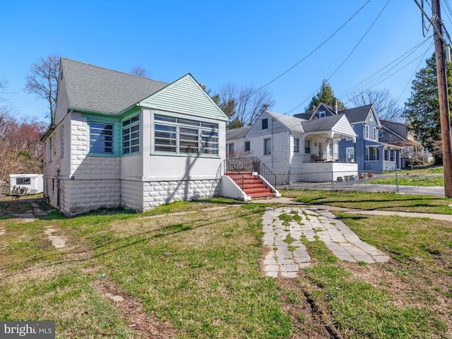 bungalow-style house with roof with shingles and a front lawn