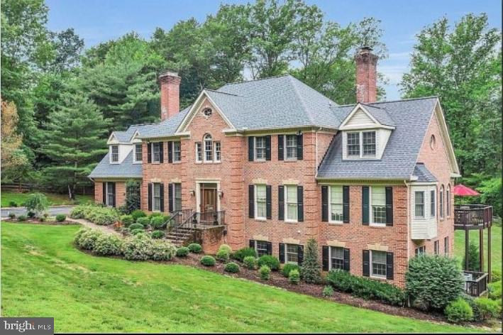 view of front of property featuring a chimney, a front yard, and brick siding
