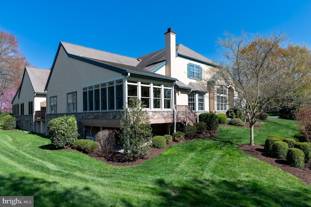 back of property featuring a yard, a chimney, and stucco siding