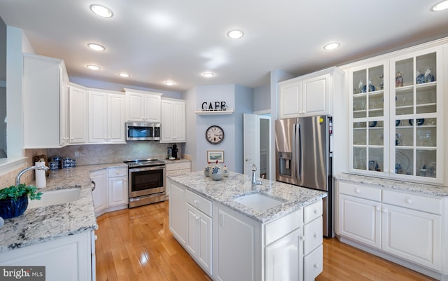 kitchen featuring white cabinetry, appliances with stainless steel finishes, an island with sink, and a sink