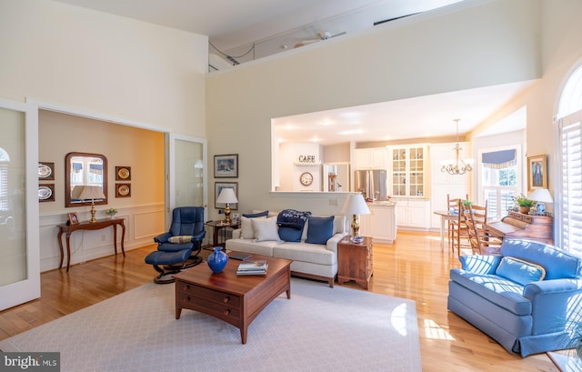living area with a high ceiling, a chandelier, and light wood finished floors
