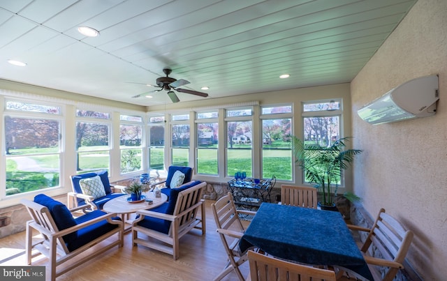 sunroom / solarium featuring a textured wall, a healthy amount of sunlight, and wood finished floors