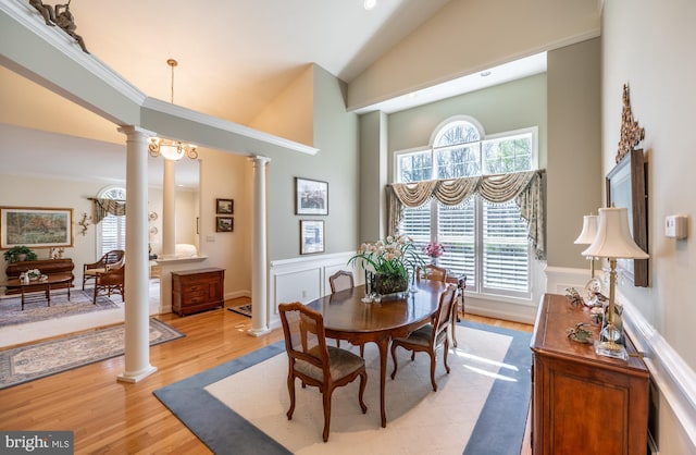 dining area featuring ornate columns, high vaulted ceiling, wainscoting, and light wood-style floors