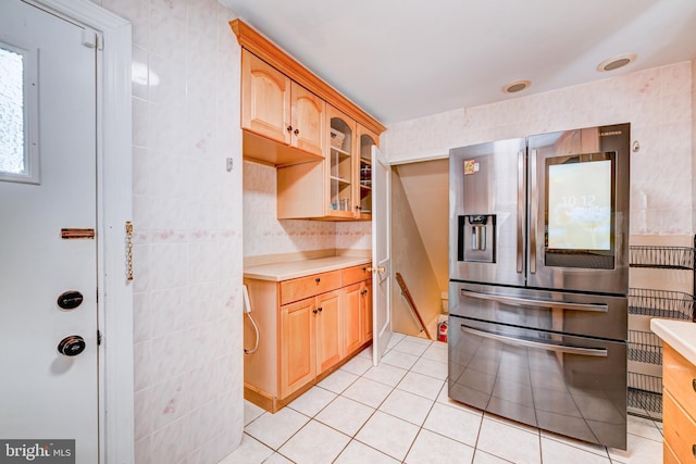 kitchen featuring light countertops, stainless steel fridge with ice dispenser, light tile patterned flooring, and glass insert cabinets