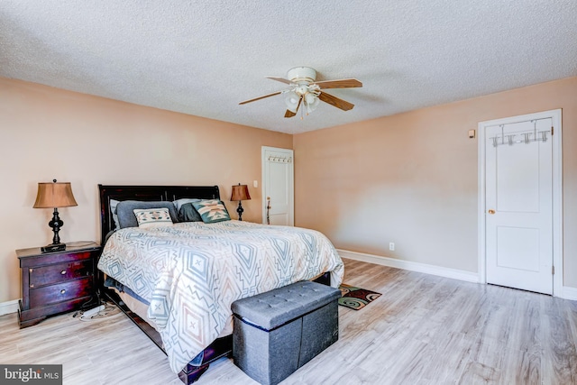 bedroom with light wood-style floors, baseboards, ceiling fan, and a textured ceiling