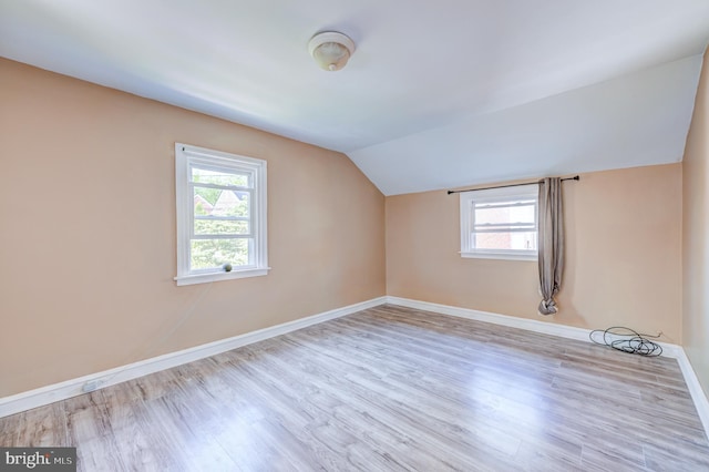 additional living space with baseboards, a wealth of natural light, wood finished floors, and lofted ceiling