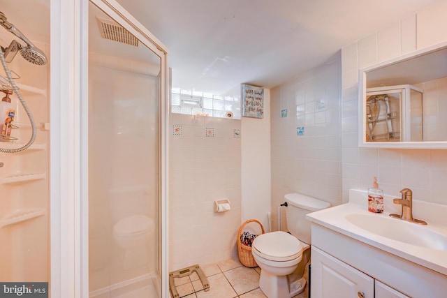 full bath with tile patterned flooring, vanity, toilet, tile walls, and a shower stall