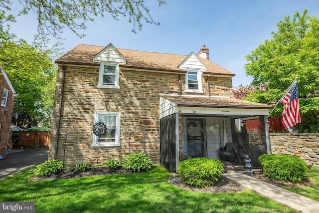 view of front of home with a front yard, fence, a chimney, and stone siding