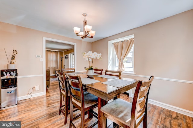 dining room featuring baseboards, light wood-type flooring, and a notable chandelier