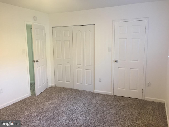 unfurnished bedroom with carpet flooring, baseboards, and a closet