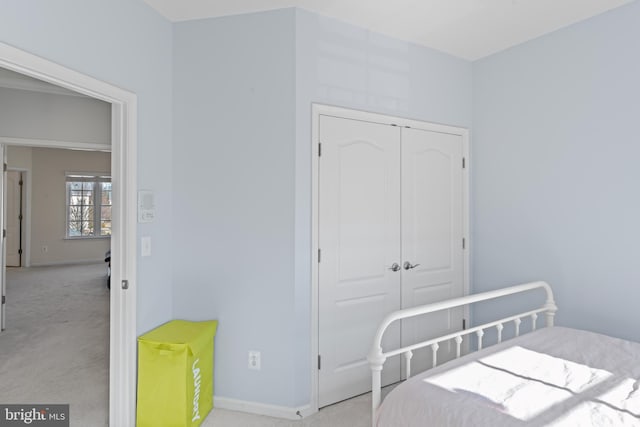 bedroom featuring a closet, baseboards, and light colored carpet