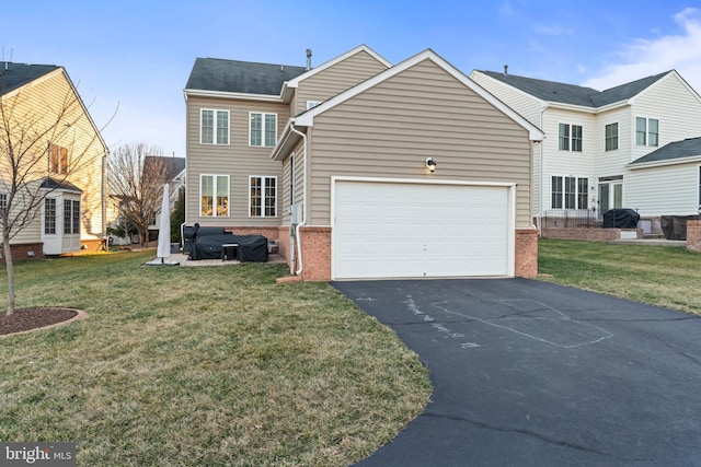 view of front facade featuring a front yard, an attached garage, brick siding, and driveway