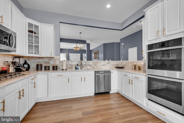 5613 Havenwood Ct, Upper Marlboro, MD 20772 - kitchen with a chandelier, stainless steel appliances, white cabinetry, light wood-style floors, and backsplash