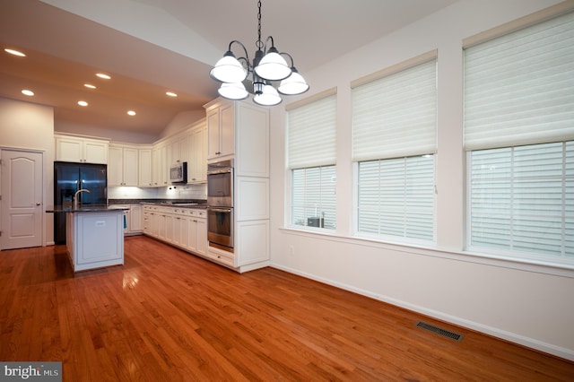 kitchen with vaulted ceiling, a chandelier, dark countertops, visible vents, and stainless steel appliances