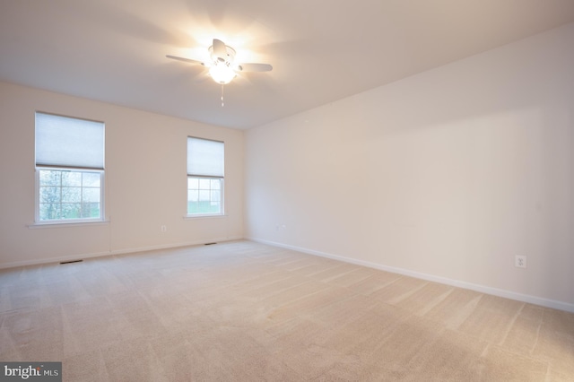 empty room with visible vents, ceiling fan, light colored carpet, and baseboards