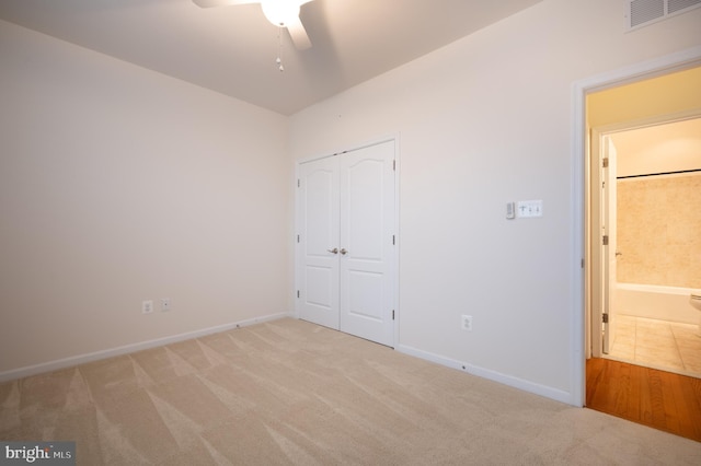 unfurnished bedroom with light carpet, a closet, baseboards, and visible vents