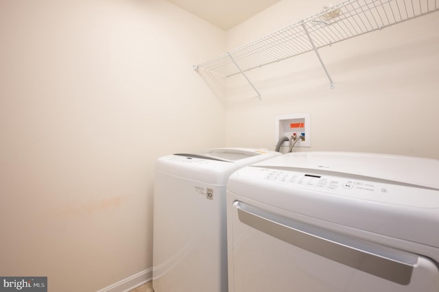 washroom with laundry area, baseboards, and washing machine and dryer