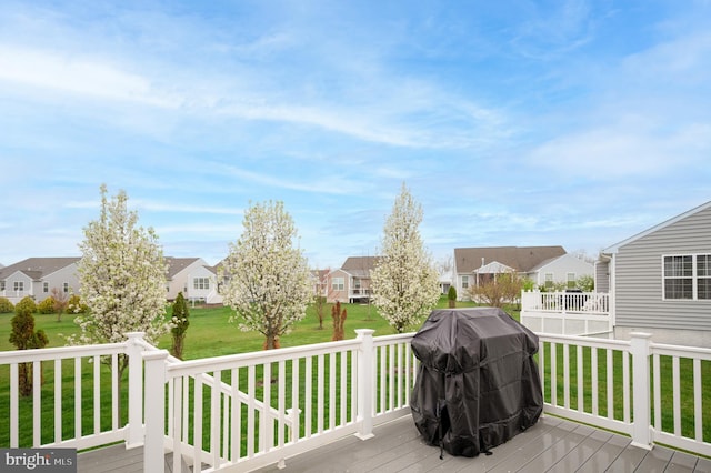 deck with grilling area, a residential view, and a lawn