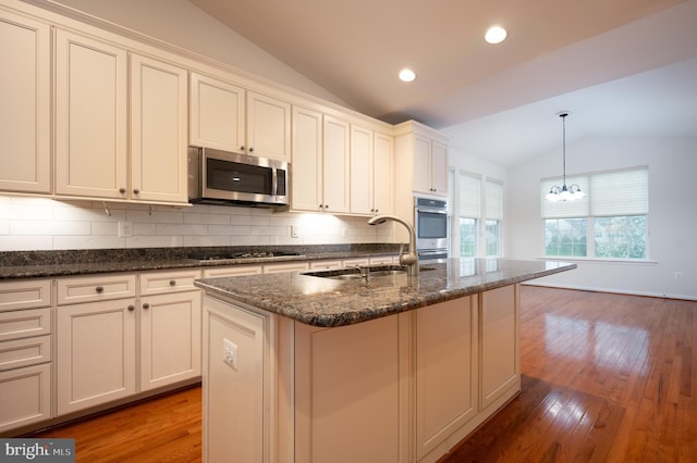 kitchen with tasteful backsplash, an inviting chandelier, lofted ceiling, stainless steel appliances, and a sink