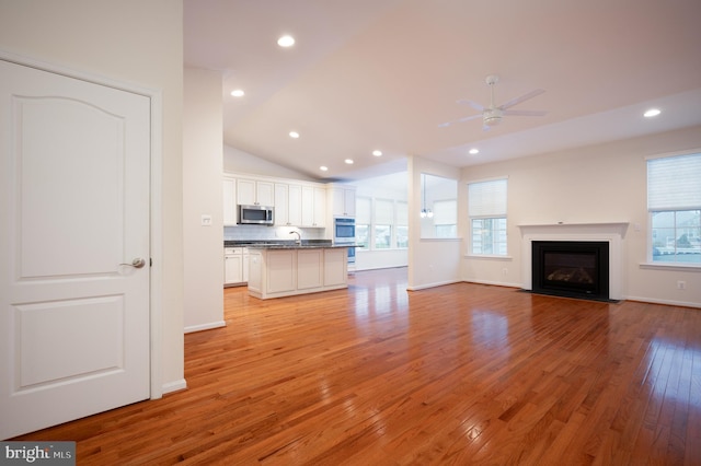 unfurnished living room featuring light wood finished floors, a healthy amount of sunlight, ceiling fan, and recessed lighting