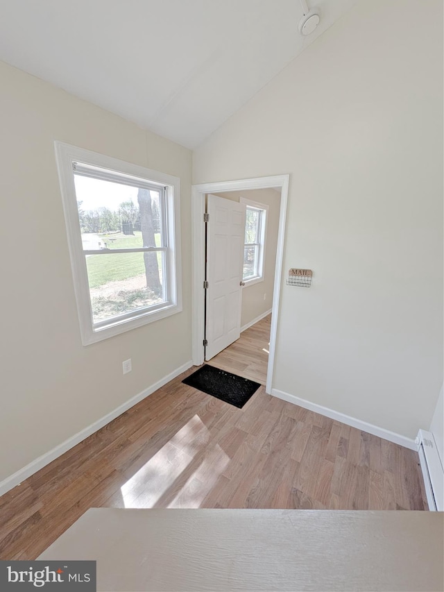 foyer with baseboard heating, vaulted ceiling, wood finished floors, and baseboards