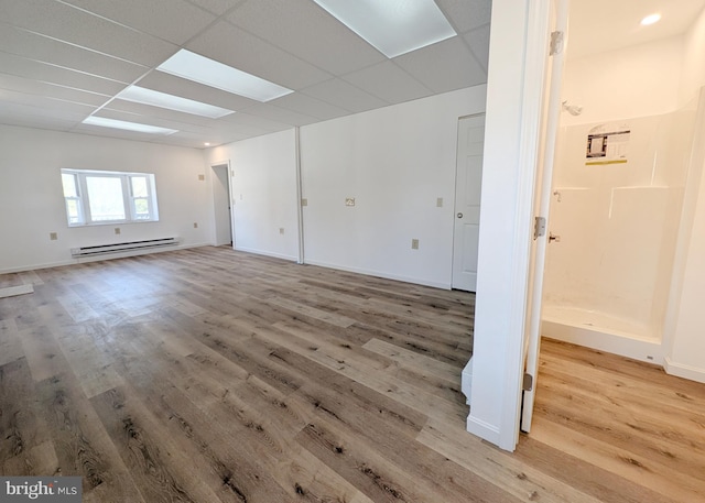 spare room with a drop ceiling, light wood-style floors, and baseboard heating