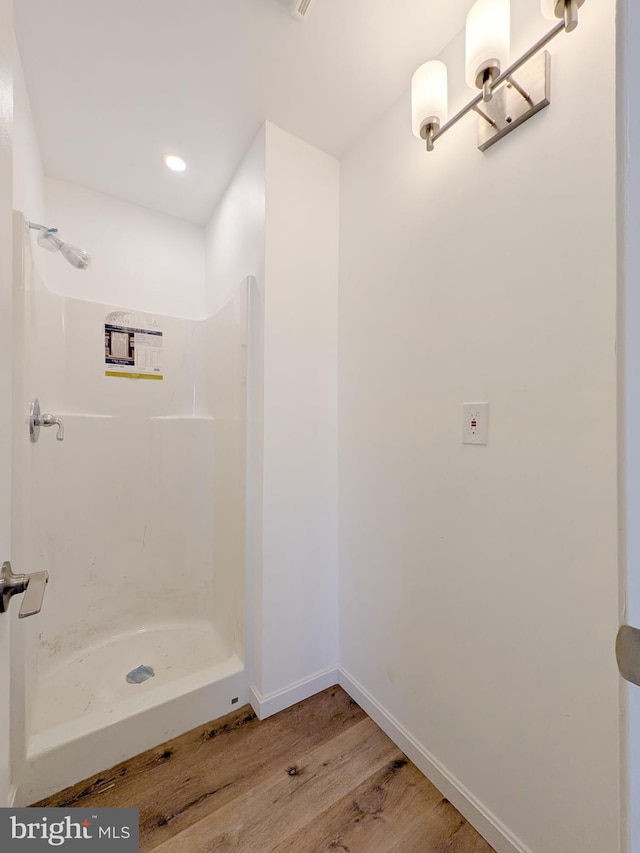 bathroom with wood finished floors, a shower stall, recessed lighting, and baseboards