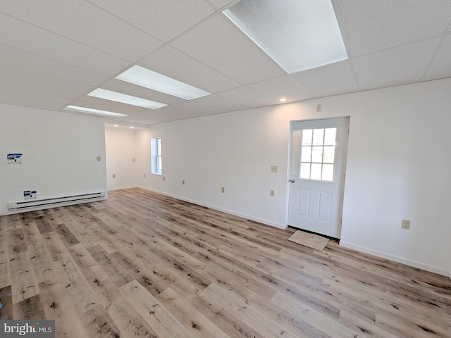 interior space with baseboard heating, baseboards, wood finished floors, and a wealth of natural light