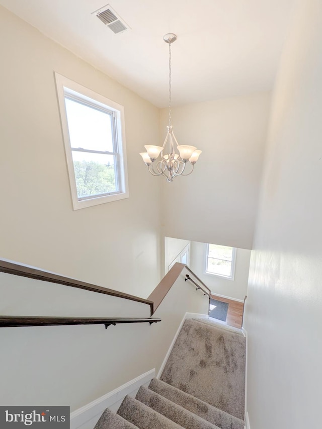 stairs featuring an inviting chandelier, wood finished floors, visible vents, and baseboards