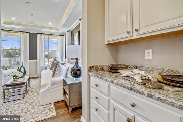 interior space featuring a raised ceiling, recessed lighting, wood finished floors, and ornamental molding