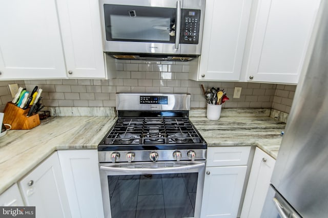 kitchen featuring white cabinets, backsplash, a ceiling fan, and appliances with stainless steel finishes